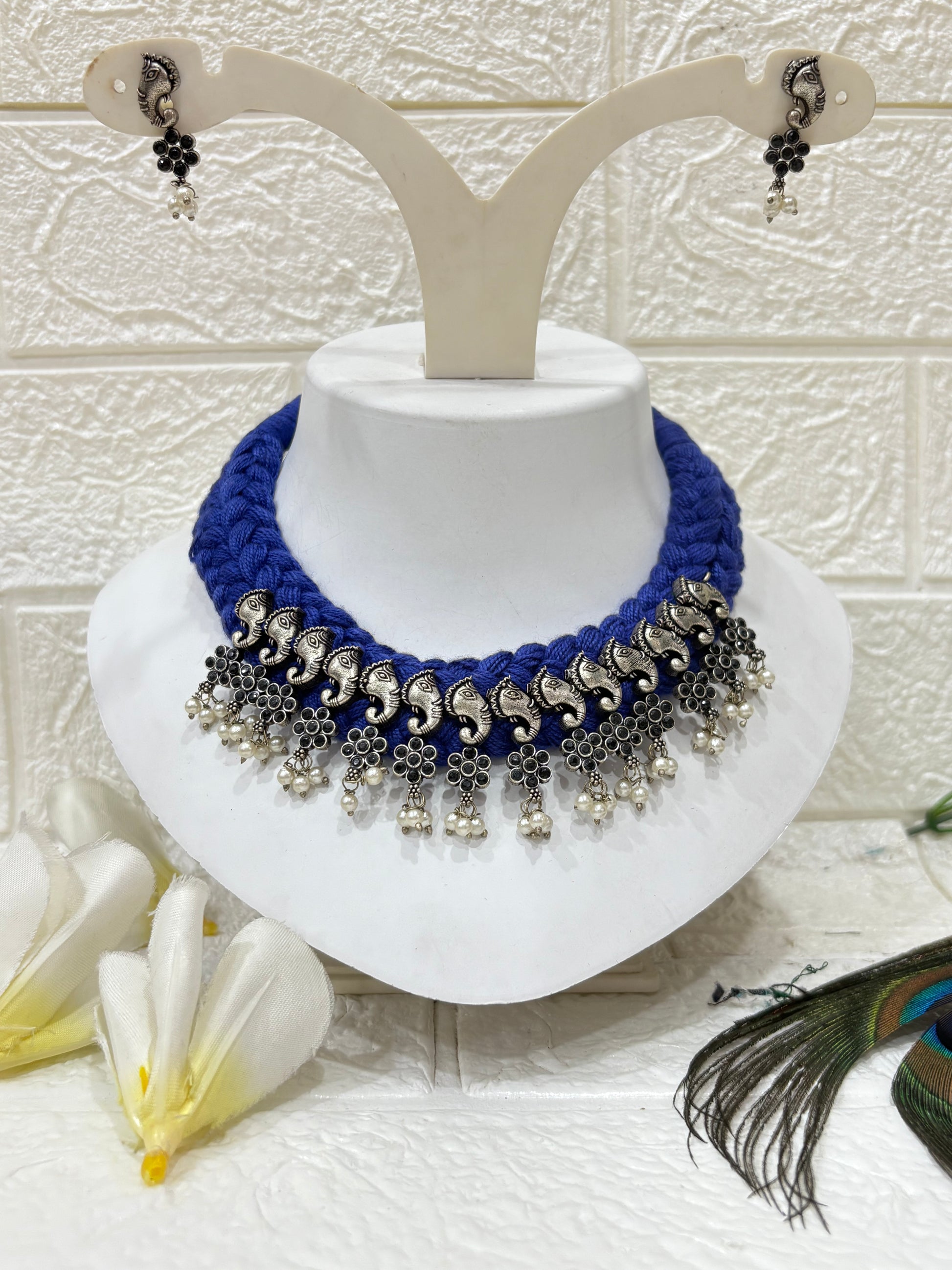 Name: Hathi Ghungroo Choker
Collection: Vanya Collection – A tribal-inspired range featuring oxidised elephant charms, floral motifs, and ghungroo drops on a vibrant blue thread base.