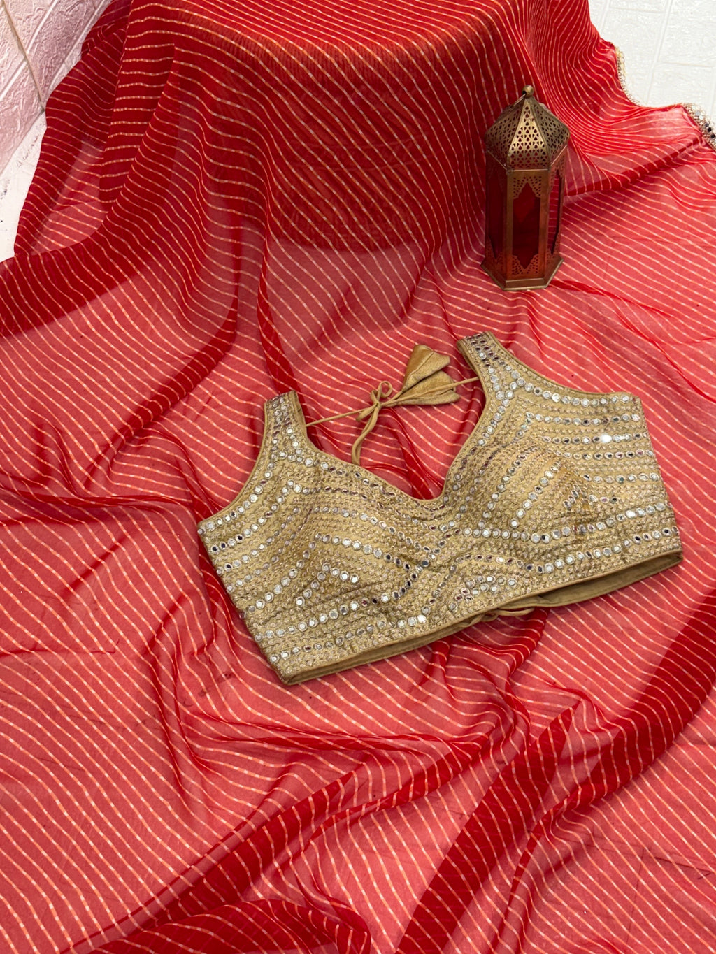 The fabric georgette rich Gold Zari weaving. International orange and mirror-work golden blouse embellishment