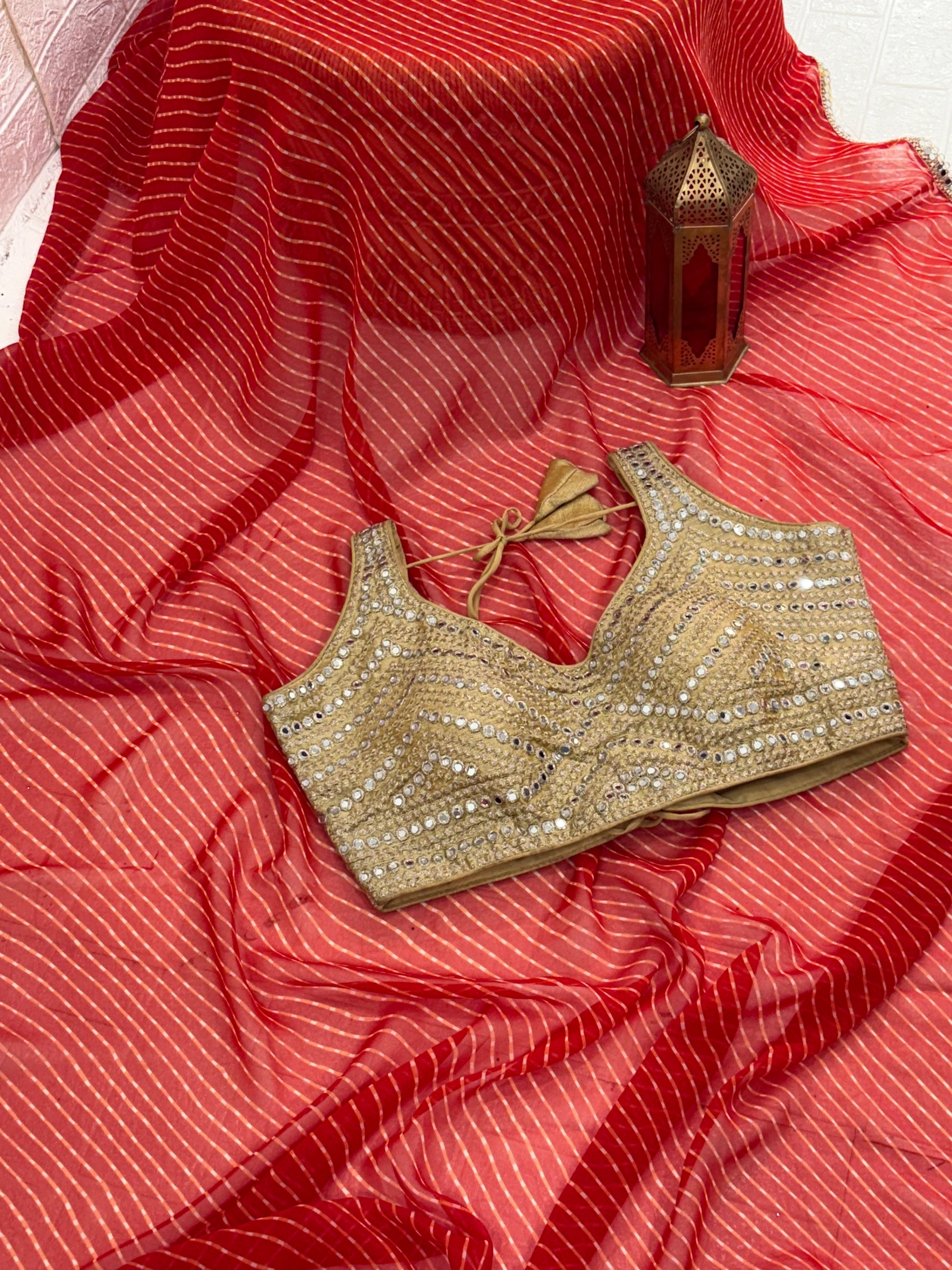 The fabric georgette rich Gold Zari weaving. International orange and mirror-work golden blouse embellishment