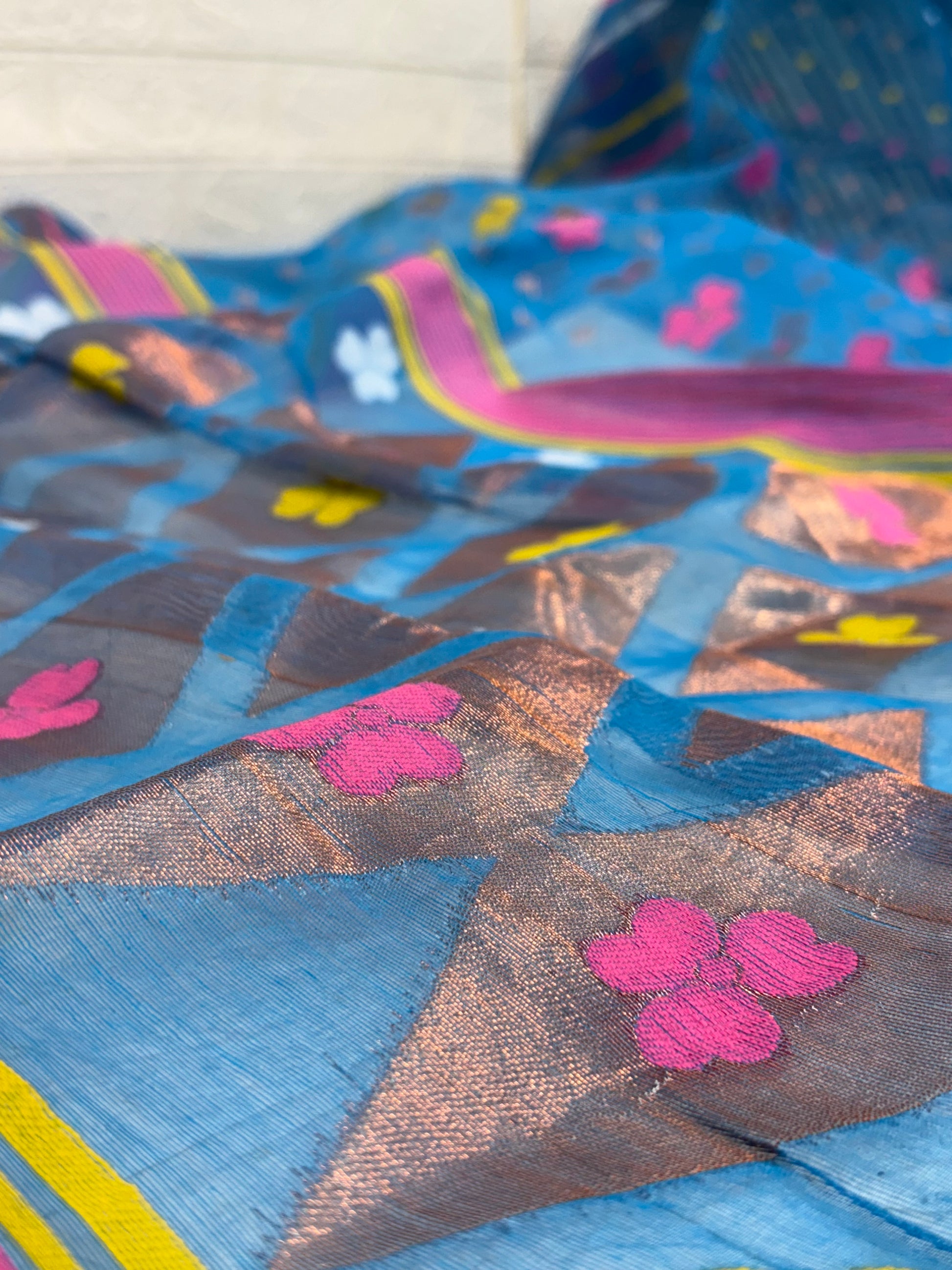 Jamdani Saree Made from airy cotton Jamdani, featuring a soothing blue base with multicolour floral butis and a beautifully woven contrast border for a fresh, elegant appeal.