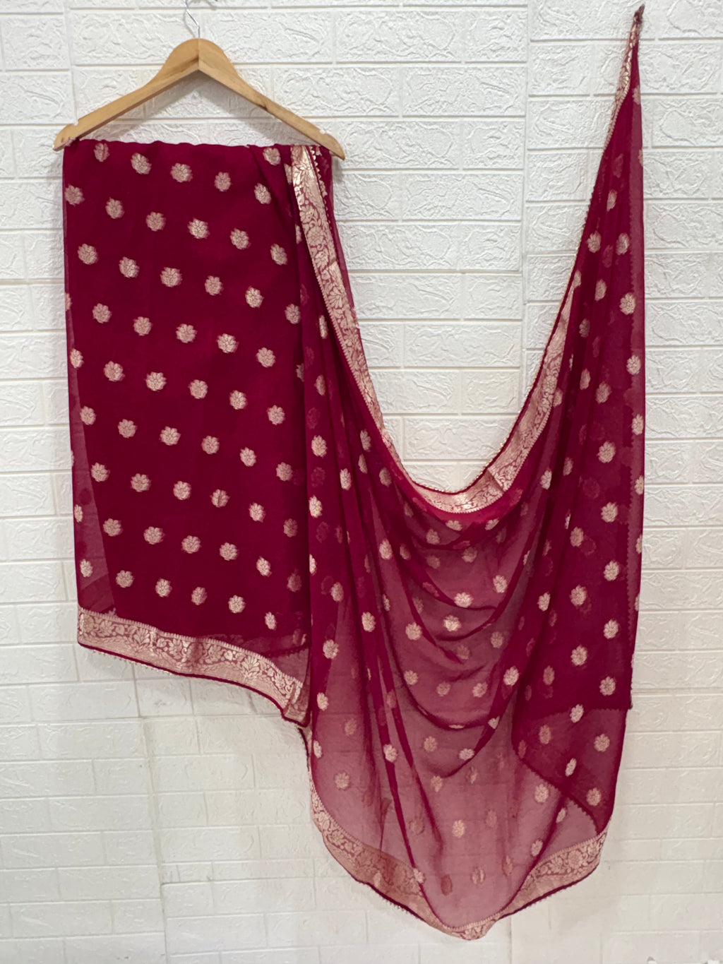 This fabric is a maroon soft Georgette with all over gold zari floral buti embroider and a rich woven border paired with a matching plain blouse perfect for festival