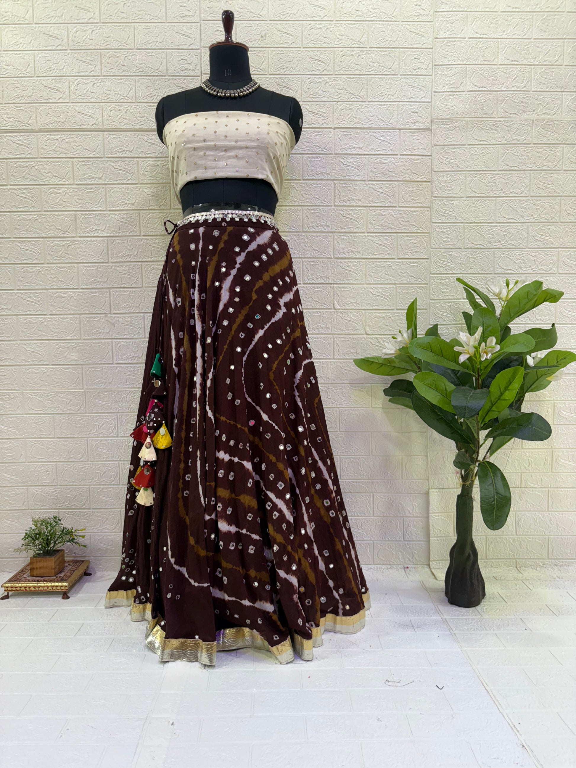 Name:
Mocha Swirl Bandhani Lehenga Crafted from rich brown soft cotton with traditional bandhani tie-dye patterns, paired with a off White soft blouse and statement tassels for a chic festive look.