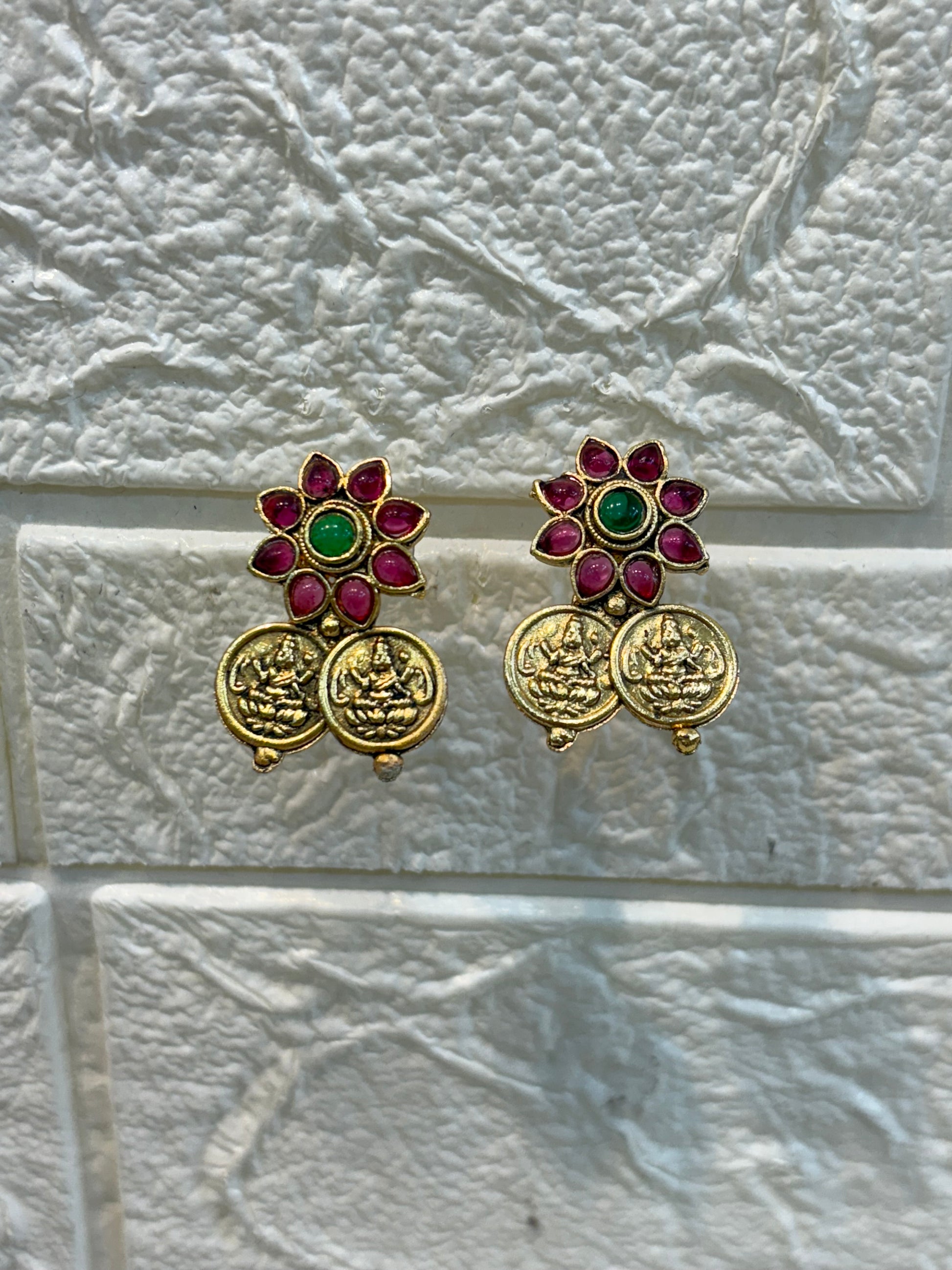 Traditional antique-finish necklace adorned with coin motifs, ruby-green floral stone work, and matching earrings—perfect for festive and wedding occasions.