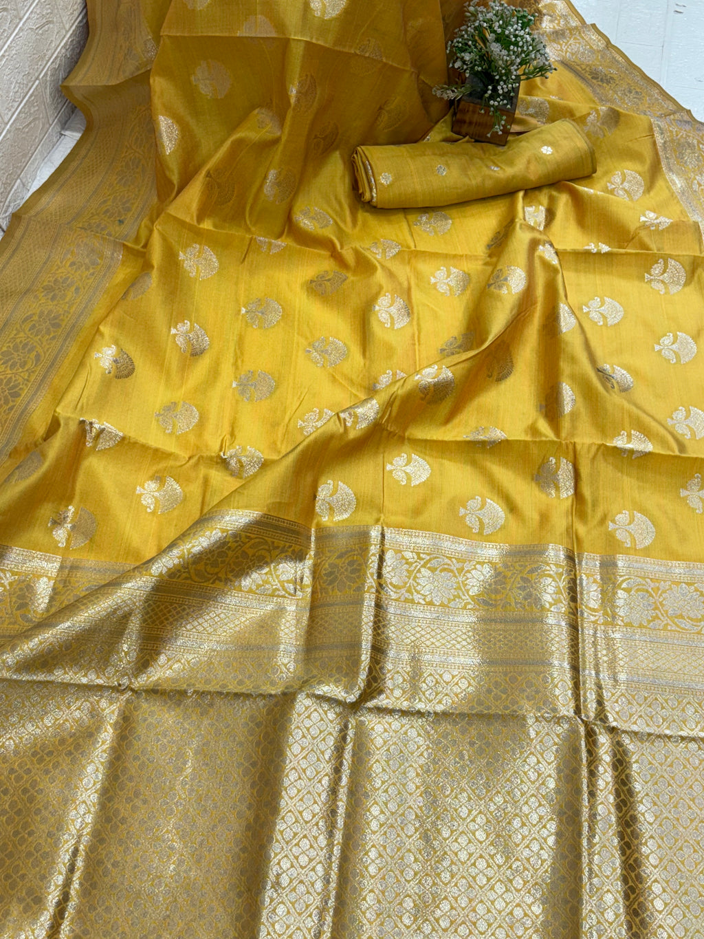 The saree appears to be a Banarasi brocade silk saree it is made of silk with rich zari (metallic thread) brocade weaving characteristic of the Banarasi style from Varanasi India the body features small fish (meen) motifs