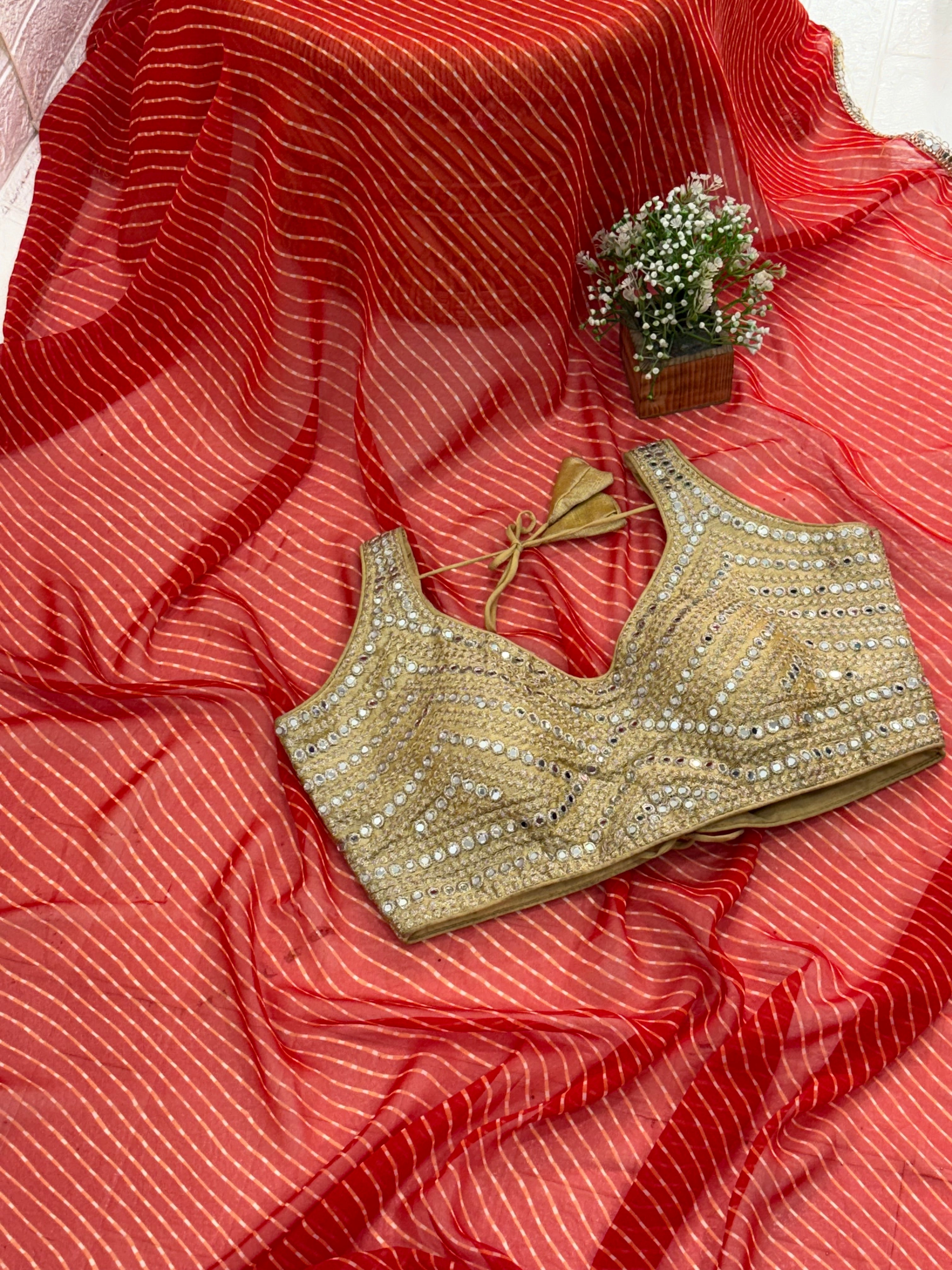 The fabric georgette rich Gold Zari weaving. International orange and mirror-work golden blouse embellishment