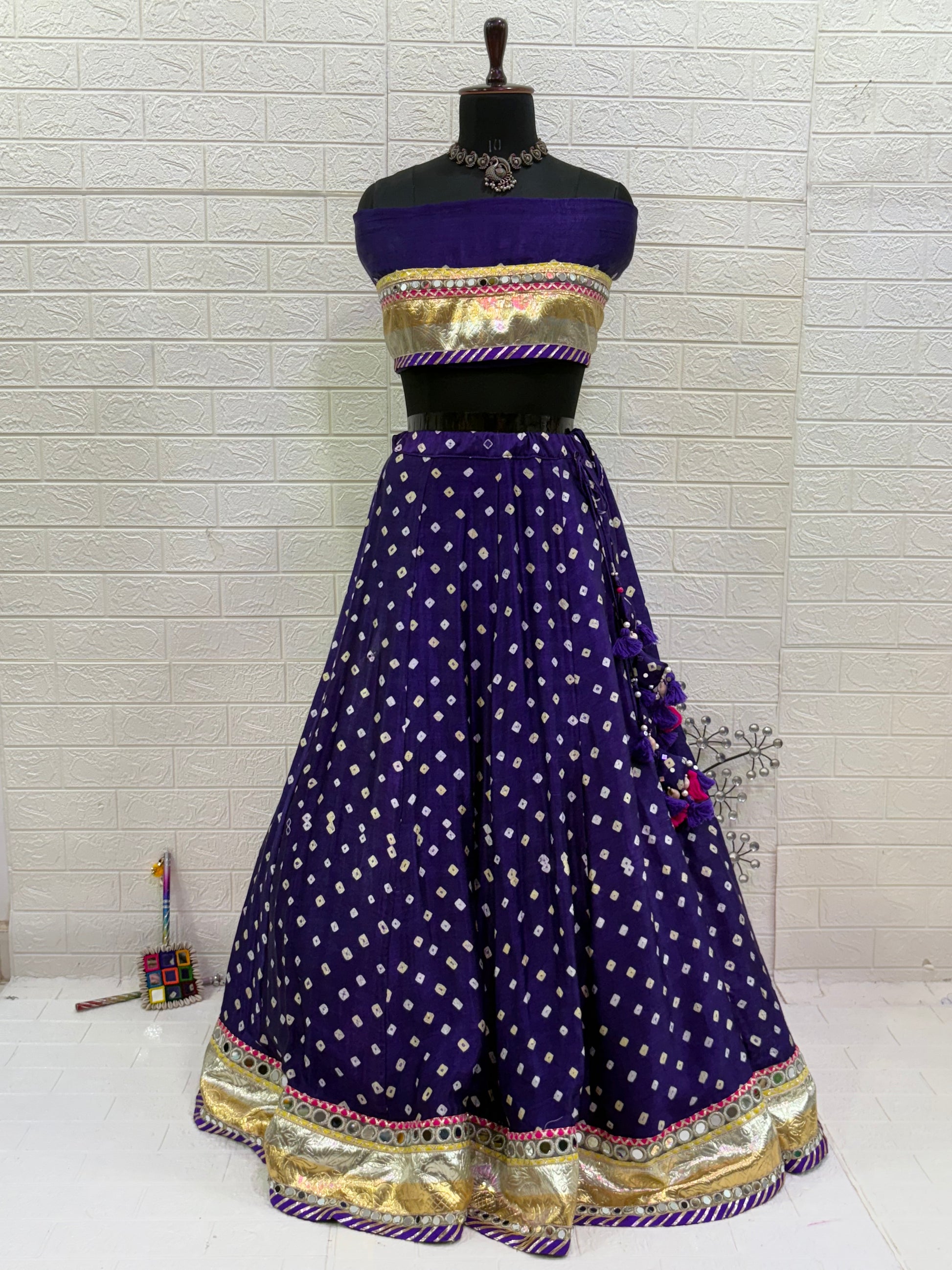 Name:
Royal Purple Bandhani Lehenga Set Made from soft synthetic satin Bandhni print with traditional paired with a contrast tie-dye dupatta and golden lace and long lumpy lace detailing for a vibrant festive look.